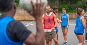 Group of athletes in sportswear engaging in passing drills while training on an outdoor court, showcasing teamwork, skill, and dedication to improving their rugby game