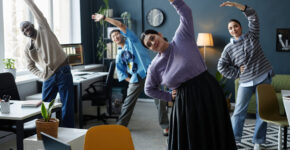 Multiethnic group of people enjoying stretching exercises starting workday in office together